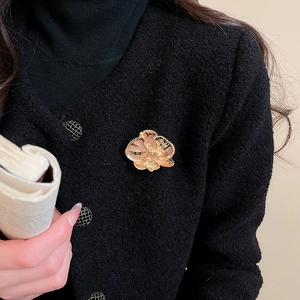 Detail of a vintage golden orchid brooch pinned on a black textured blazer jacket
