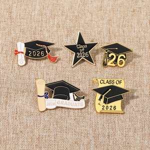Macro shot of 2026 graduation enamel pins featuring caps, stars and diploma scrolls