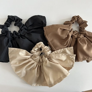 Three elegant satin ruffled scrunchies in black, brown, and beige with bow detail
