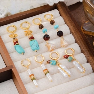 Detailed macro shot of vintage bohemian earrings with pearls and turquoise on a wood tray