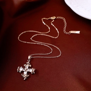 Detailed view of a rose gold zircon cross pendant on elegant dark red silk fabric