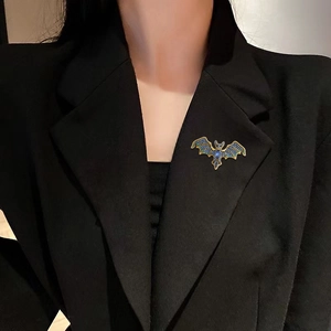 Vintage bat brooch with gold base and blue crystals pinned on a black suit lapel