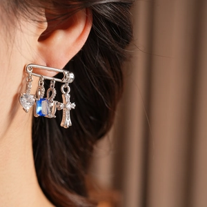 Detailed view of silver safety pin earrings with zircon heart and engraved cross