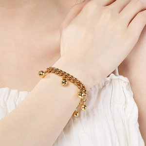 Close-up of a 18K gold plated bell charm bracelet on a model's wrist with soft lighting