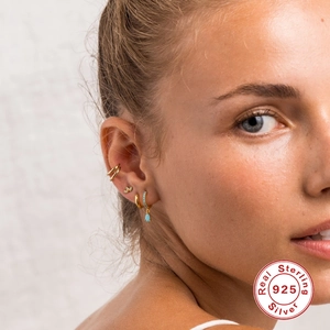 Close-up of gold S925 sterling silver hoop earrings with turquoise pendants on model