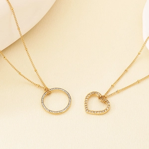Dettaglio collana dorata con ciondoli a cerchio e a cuore decorati con cristalli