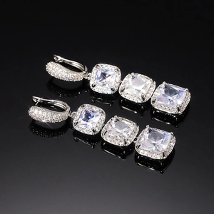 Macro shot of silver drop earrings featuring triple square-cut zircons on a black surface