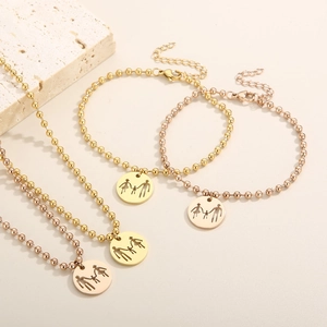 Detail of round pendant necklaces and bracelets with family silhouette in gold finish