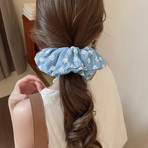 Close-up of light blue scrunchie with white floral embroidery on hair ponytail