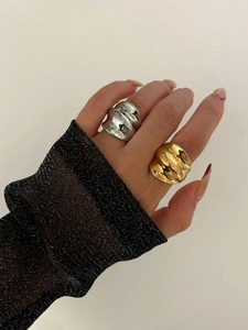 Detail of chunky gold and silver wavy statement rings worn on fingers