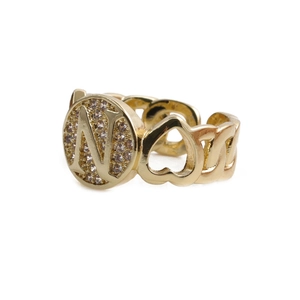 Macro detail of golden N-letter ring with heart cutouts and pavé stones in chain style