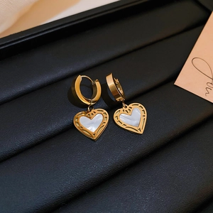 Detail shot of heart-shaped gold-plated earrings with shell inlay and hollow patterns