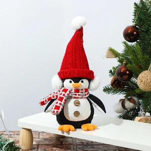 Close-up of plush glowing penguin with knitted hat on wooden stand with Christmas decor