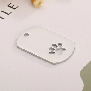 Close-up of polished stainless steel dog tag with a hollow cat paw cutout design