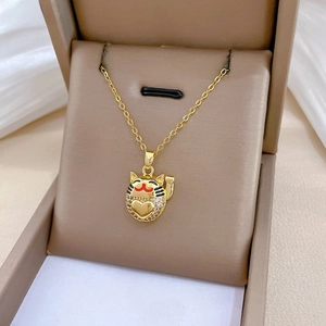 Close-up of golden lucky cat pendant with heart-shaped crystal inlay on a beige jewelry box
