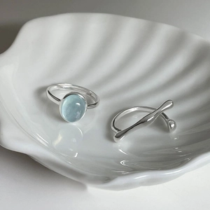 Elegant set of S925 silver rings with light blue gemstone displayed on a white shell
