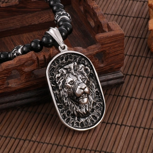 Detailed close-up of retro stainless steel lion head pendant on black beaded necklace