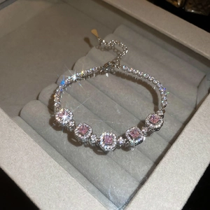 Close-up of pink square gemstones and diamonds on a silver tennis bracelet in a box