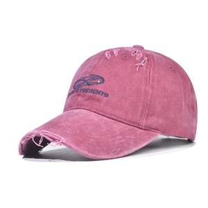 Detail of vintage washed pink baseball cap with blue embroidery and distressed edges