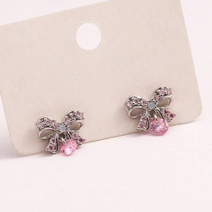 Close-up of silver bow stud earrings with pink zircon and clear crystals on card