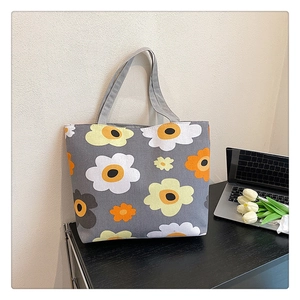 Detailed view of grey canvas tote bag with large floral print next to white tulips