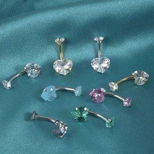 Stainless steel heart zircon belly rings in multiple colors on a cyan satin background