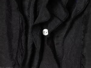 Gros plan détaillé d'un bouton blanc sur une chemise noire à volants de style français
