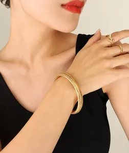 Close-up of gold Tubogas snake bracelet with leaf and diamond rings on model wrist
