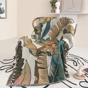 Macro detail of tropical leaf pattern woven throw blanket with fringe edge on chair