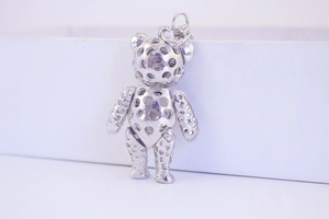 Close-up of a silver hollow metal bear pendant keychain with detailed cutout design