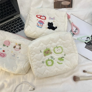 Three quilted pouches featuring fruit and animal embroidery on soft cream heart-patterned fabric