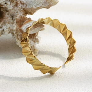 Détail d'un bracelet en acier inoxydable doré avec texture géométrique ondulée