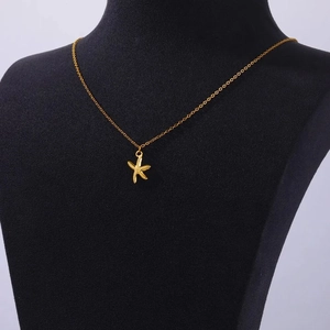 Detailed view of a gold starfish pendant on a delicate chain over black velvet display