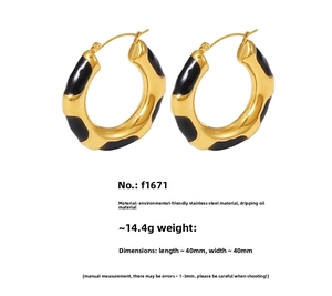 Detail view of 40mm wavy gold stainless steel hoop earrings with black enamel pattern