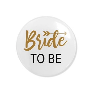 Macro shot of white and gold Bride TO BE badge with elegant arrow design detail