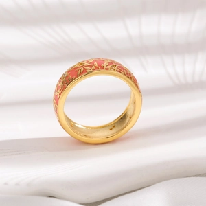 Macro shot of gold ring featuring pink enamel floral texture and white zircon stones