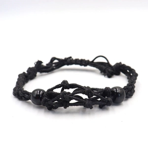 Detailed view of black handcrafted woven cord bracelet with polished beads and knots
