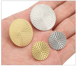 Détail de boucles d'oreilles rondes texturées or et argent montrant l'échelle de taille