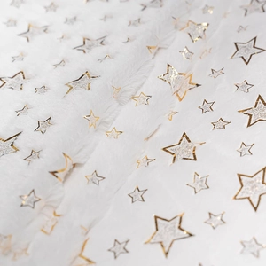 Close-up of white plush fabric with metallic gold and silver snowflake pattern detail