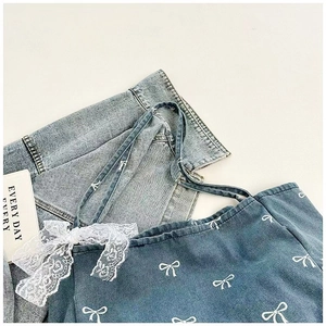 Close-up of blue denim tote bag with white bow prints and delicate lace ribbons