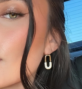 Detailed view of elegant gold U-shaped earrings with micro-pave white crystals on model
