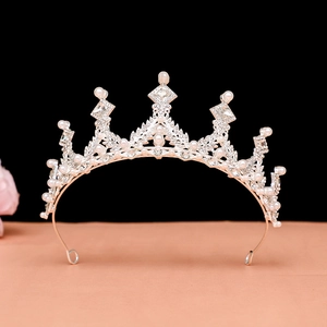 Detailed close-up of a silver baroque crown with white pearls and sparkling rhinestones