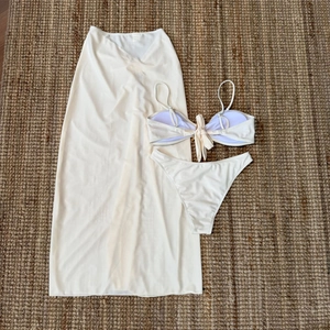 Vue à plat d'un ensemble bikini blanc crème avec jupe longue en tulle sur paille