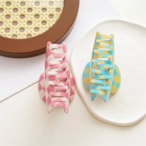 Close-up of pink and blue checkerboard hair claws on a textured white tray display