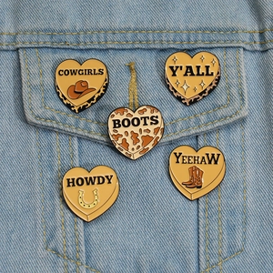 Detailed set of five Western cowboy style heart enamel pins on blue denim fabric