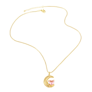 Macro detail of gold moon pendant with pink heart gemstone and sparkling crystals