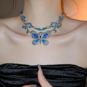 Gros plan d'un collier double rang avec papillon en cristal bleu et perles blanches