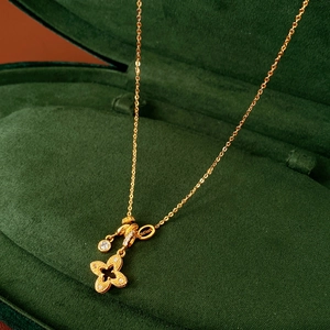 Detailed close-up of golden hollow clover pendant necklace in green velvet jewelry box