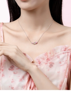 Detail of S925 silver necklace with pink heart gemstone and star pendant on a model