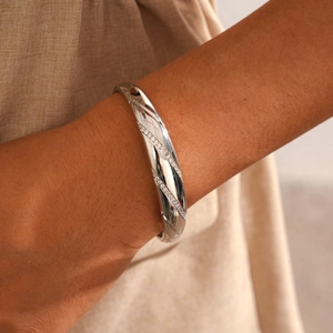 Detail of silver twisted bangle with pave-set cubic zirconia on female wrist